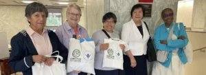 Five women standing with tote bags and information