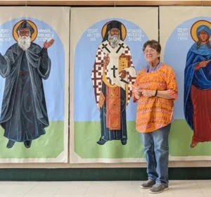 A woman standing in front of three life-size religious icon paintings