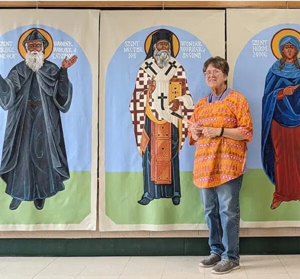 A woman standing in front of three life-size religious icon paintings