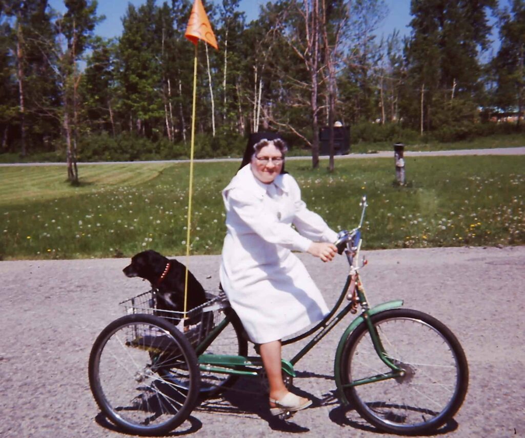 Hamburg, N.Y. - Our Lady of Charity Sr. Bernadette Garrity in 1978 riding a bike with her dog.