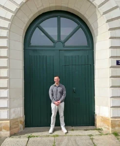 JJ in front of the green door at the Motherhouse in Angers, France, during the 2026 pilgrimage.