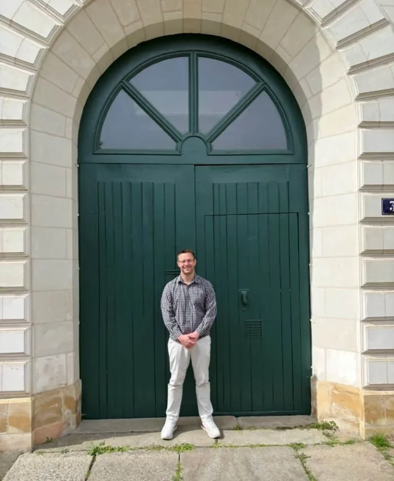 JJ in front of the green door at the Motherhouse in Angers, France, during the 2026 pilgrimage.