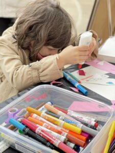 little girl squeezing glue onto artwork
