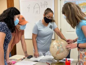 Teacher and students looking at world globe at DeNeuville Learning Center for Women